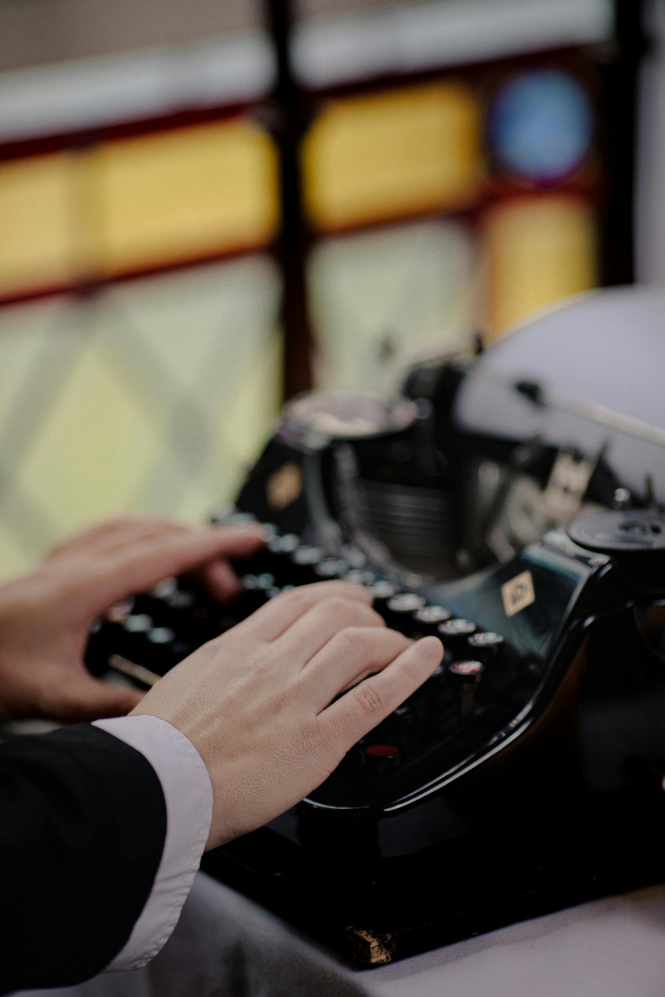 Home 6 Close-up of hands typing on a vintage typewriter in classic setting.