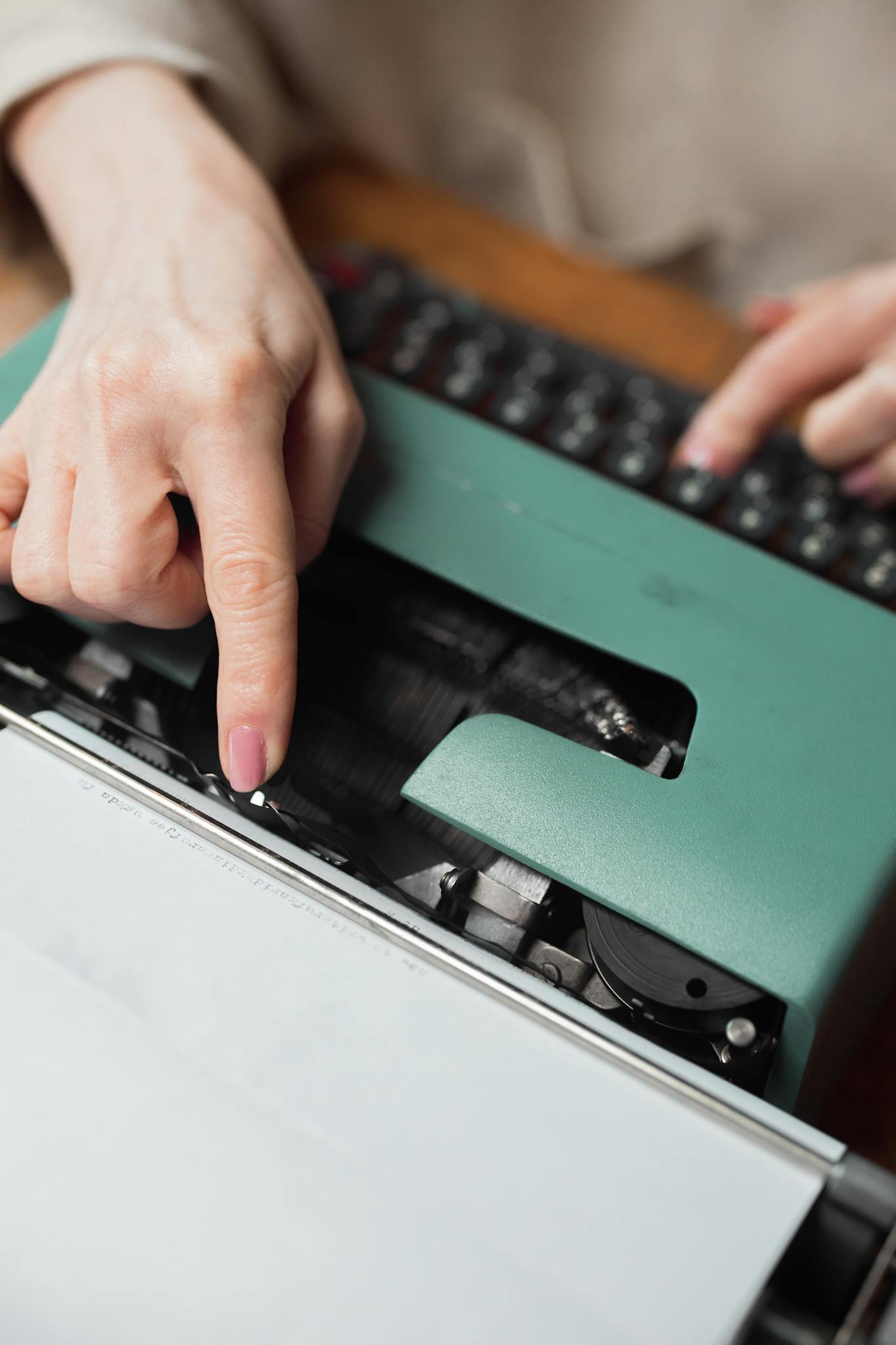 About 3 Hands typing on a green vintage typewriter, focusing on the mechanical keys and action.